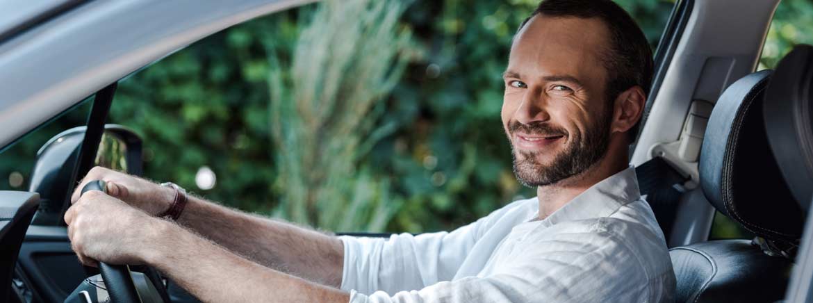 A man smiling while driving his car